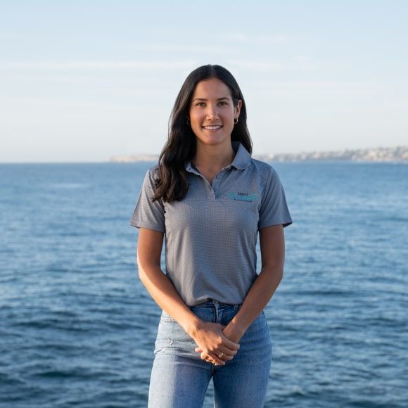 Emma, co-founder and business administrator, standing in front of the ocean.