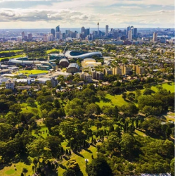 Centennial Park landscape with trees and distant city skyline.