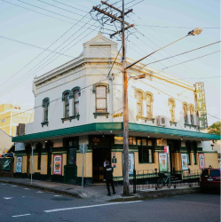 Lively Newtown street lined with historic architecture and leafy footpaths.