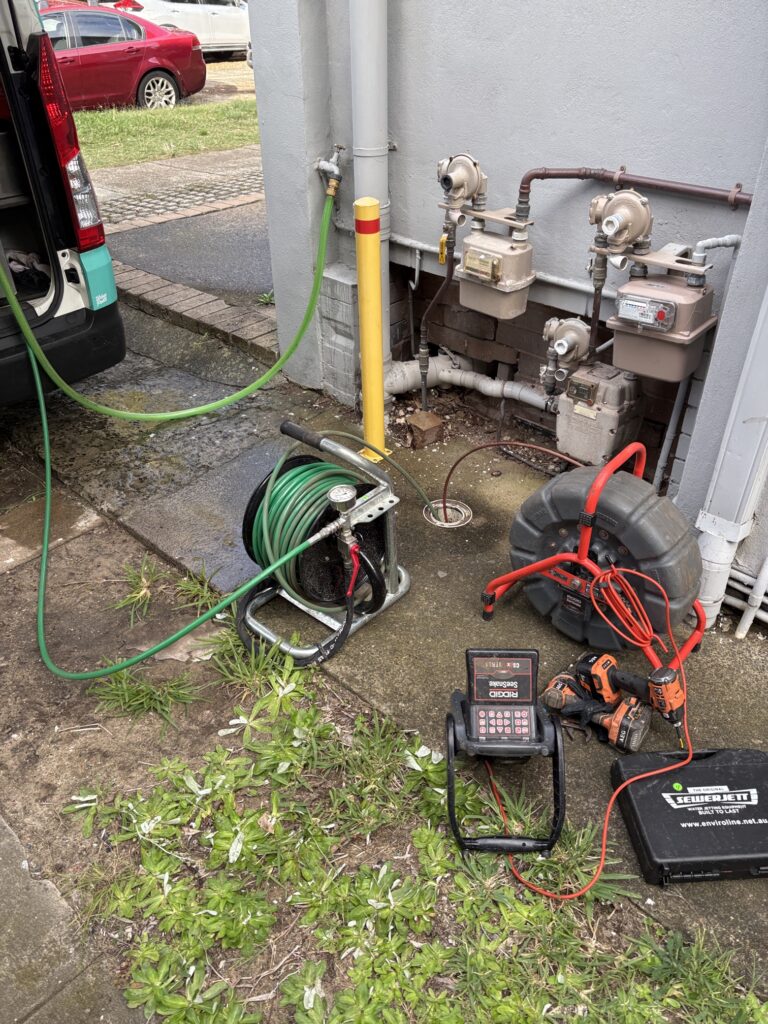 Plumbers using a jet blasting tool to clear a blocked drain
