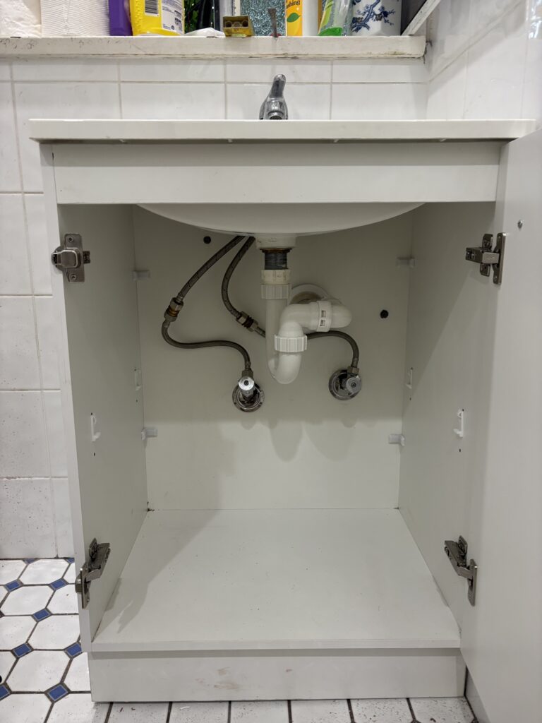 Under-sink plumbing setup by a Randwick plumber, showing clean pipework and fittings inside a bathroom vanity.