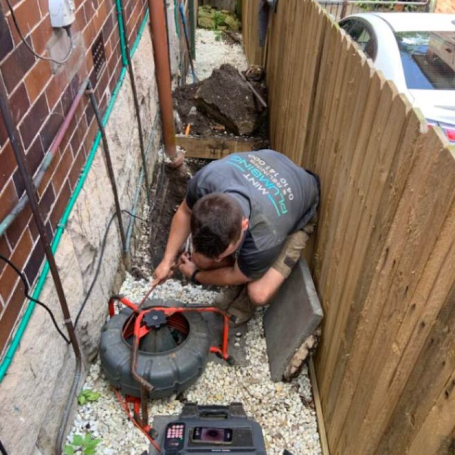 Plumber performing sewer pipe repair outdoors.
